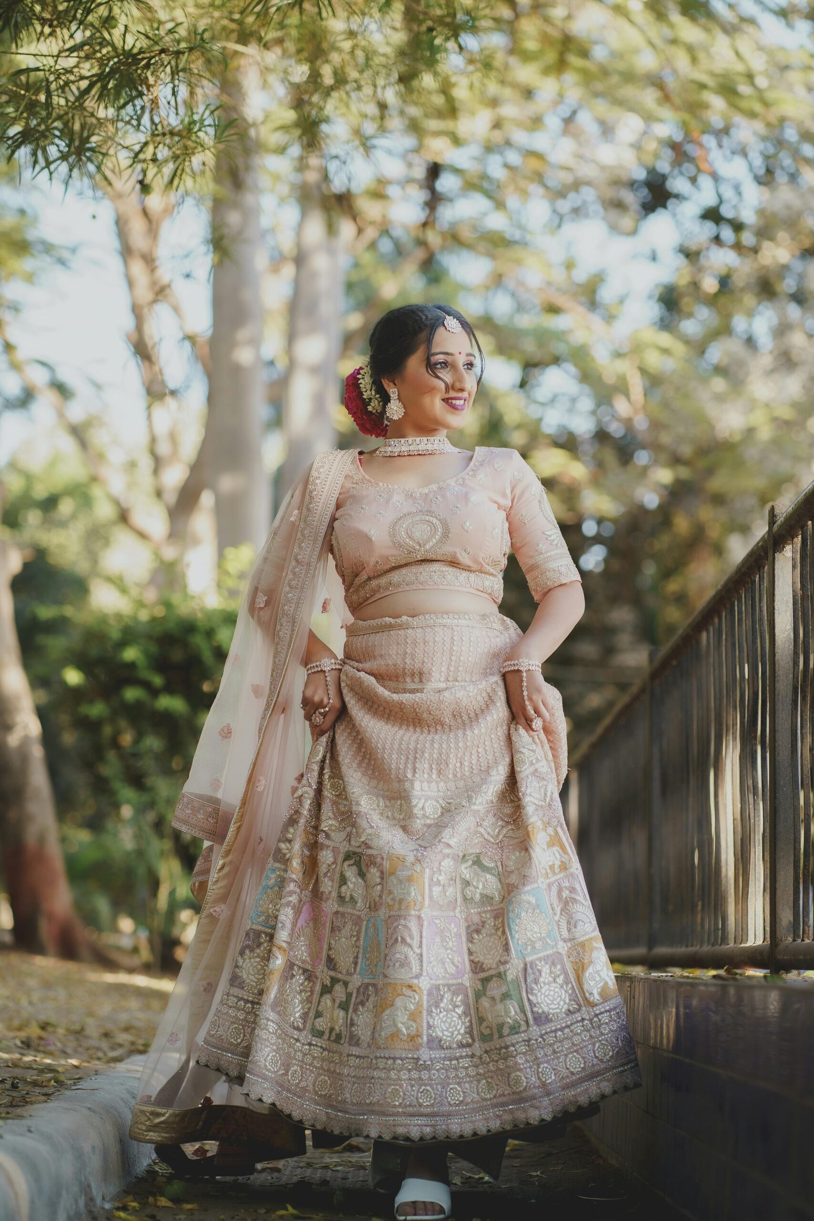 Beautiful bride in traditional South Asian wedding attire smiling outdoors.